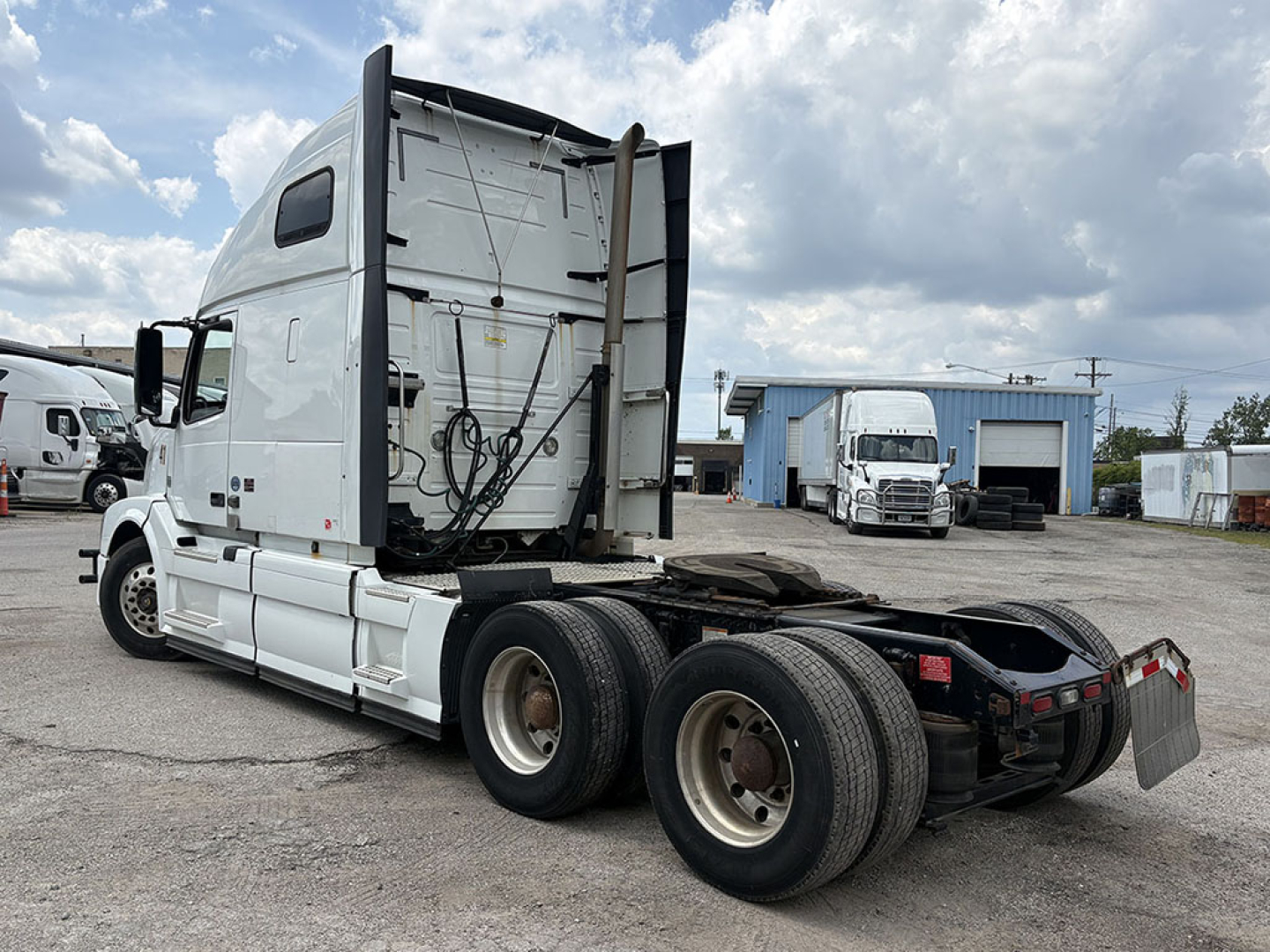 Volvo VNL 670 sleeper tractor in a parking yard with rear view showing fifth wheel and dual rear axles.