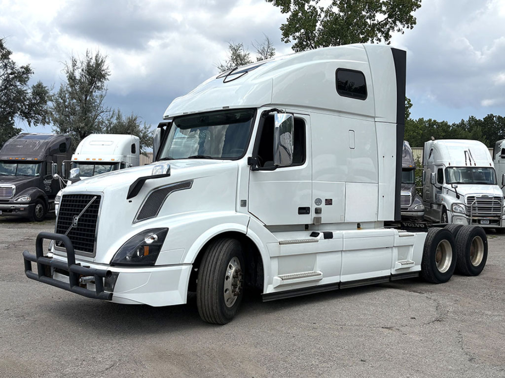 Volvo VNL 670 sleeper cab tractor in white with bumper guard, side mirrors, and large aerodynamic cab; visible front grille, headlights, and dual rear wheel configuration.