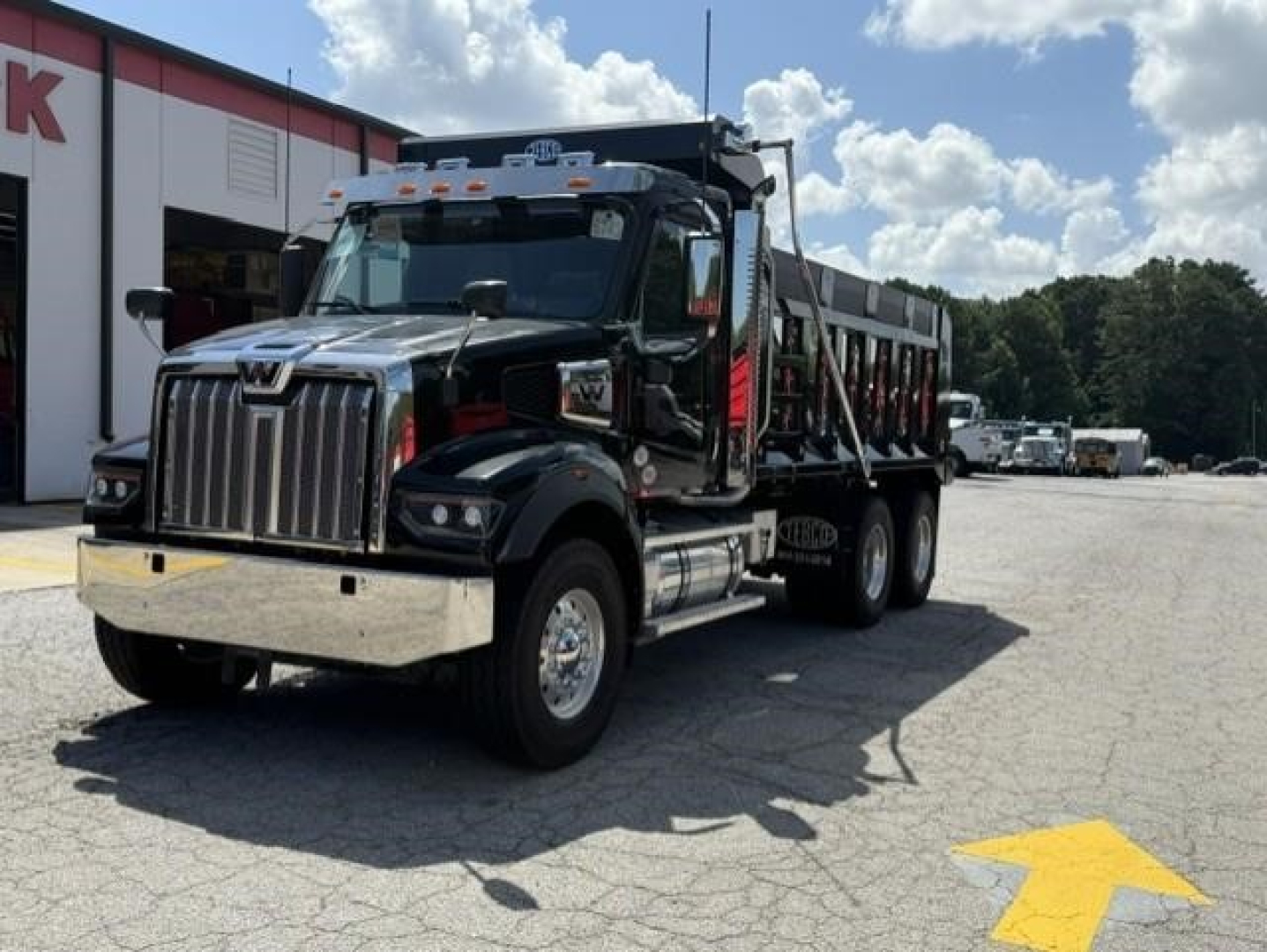 Western Star 47X dump truck in a parking lot, glossy black cab with chrome grille and bumper, dump bed visible on a sunny day.