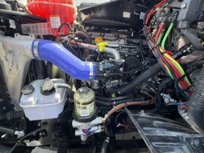 Truck engine bay with blue silicone hose, white reservoir, and various colorful wiring harnesses visible in a Western Star 47X engine compartment.