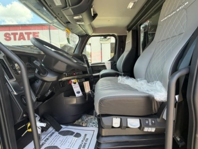 CAB interior of a new Western Star 47X dump truck showing the driver seat, steering wheel, and dashboard with protective coverings on seats.