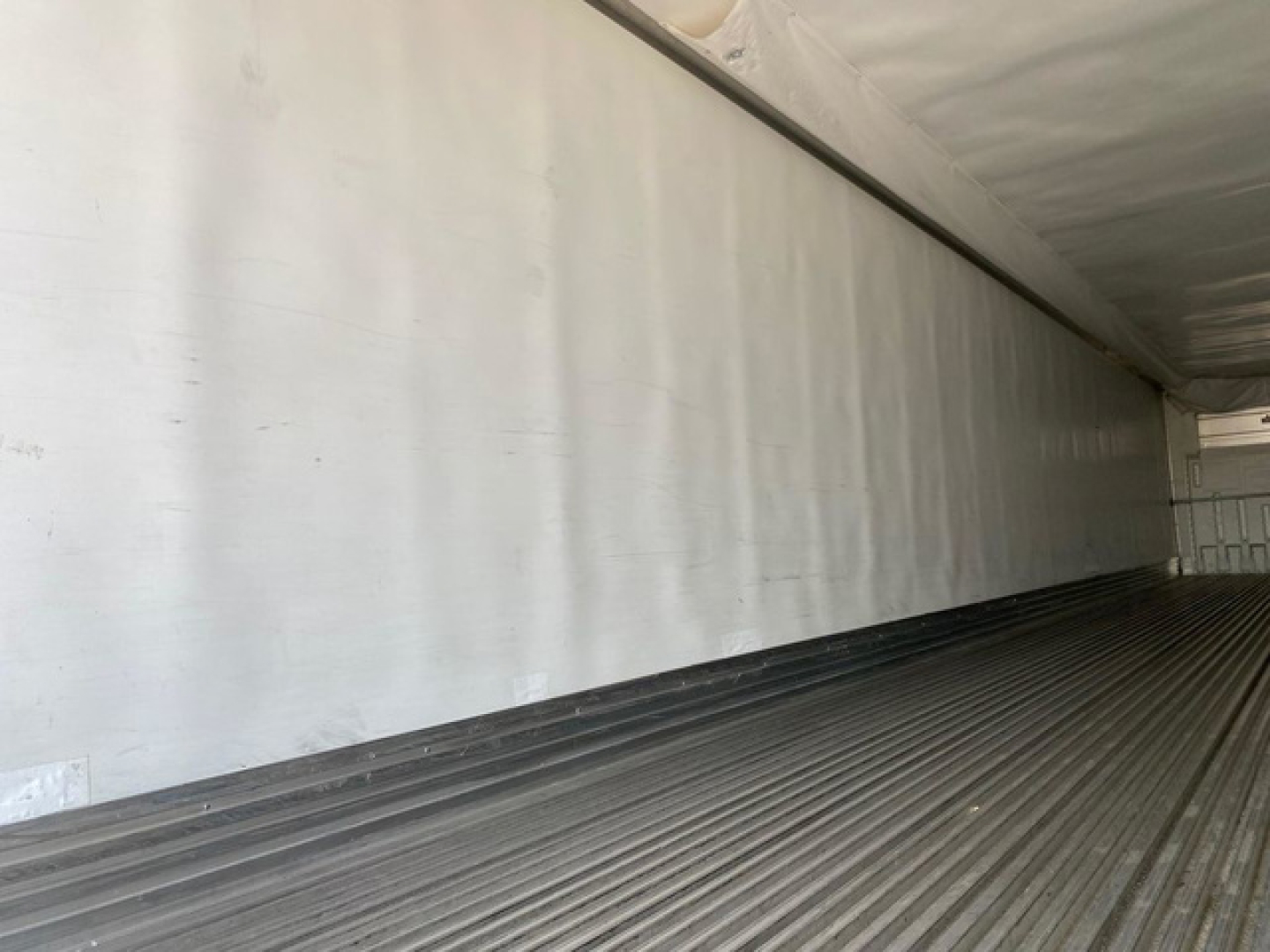 Trailer interior wall and floor of a refrigerated utility trailer shown with ribbed metal floor and blank white wall panels.