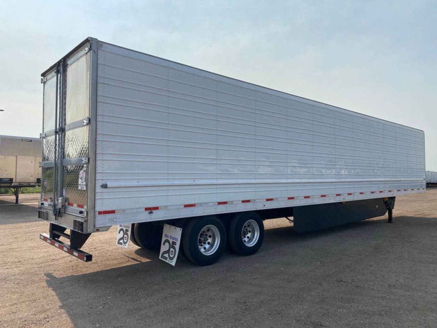 Trailer side view of a 2021 Utility reefer loaded module showing silver aluminum panels and tandem axles.