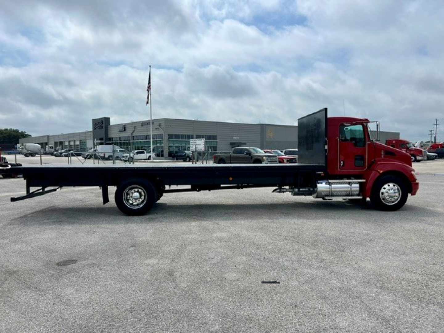 Kenworth T270 flatbed truck side view showing long flatbed with red cab and black chassis