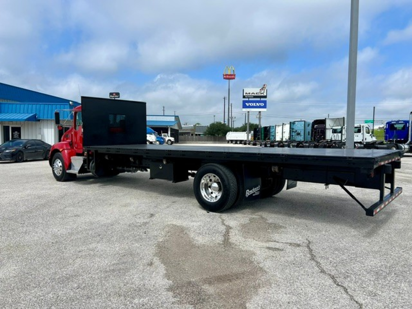 Kenworth T270 flatbed truck in-service showing long flatbed with black deck and red cab, 2-axle configuration, with toolbox and rear under-structure visible.