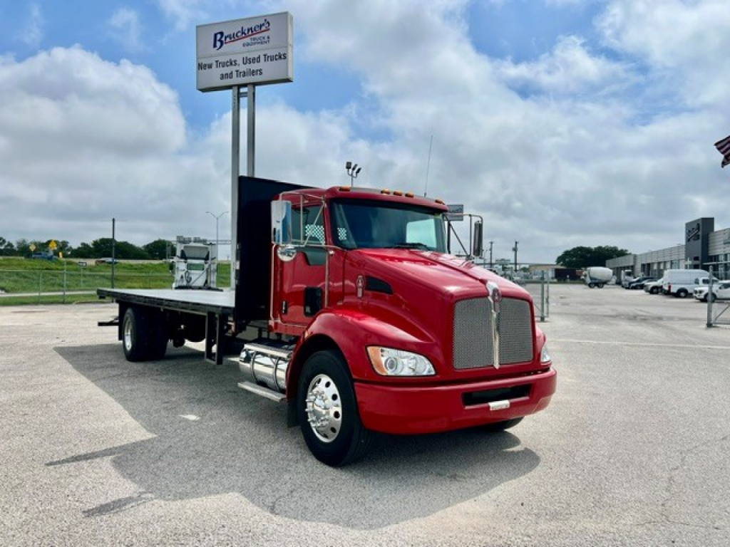 Kenworth T270 flatbed truck in red, front three-quarter view, with flatbed and tall sign in background.