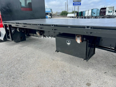 Kenworth flatbed truck side view showing underbody toolbox and frame with storage box and mounting hardware.