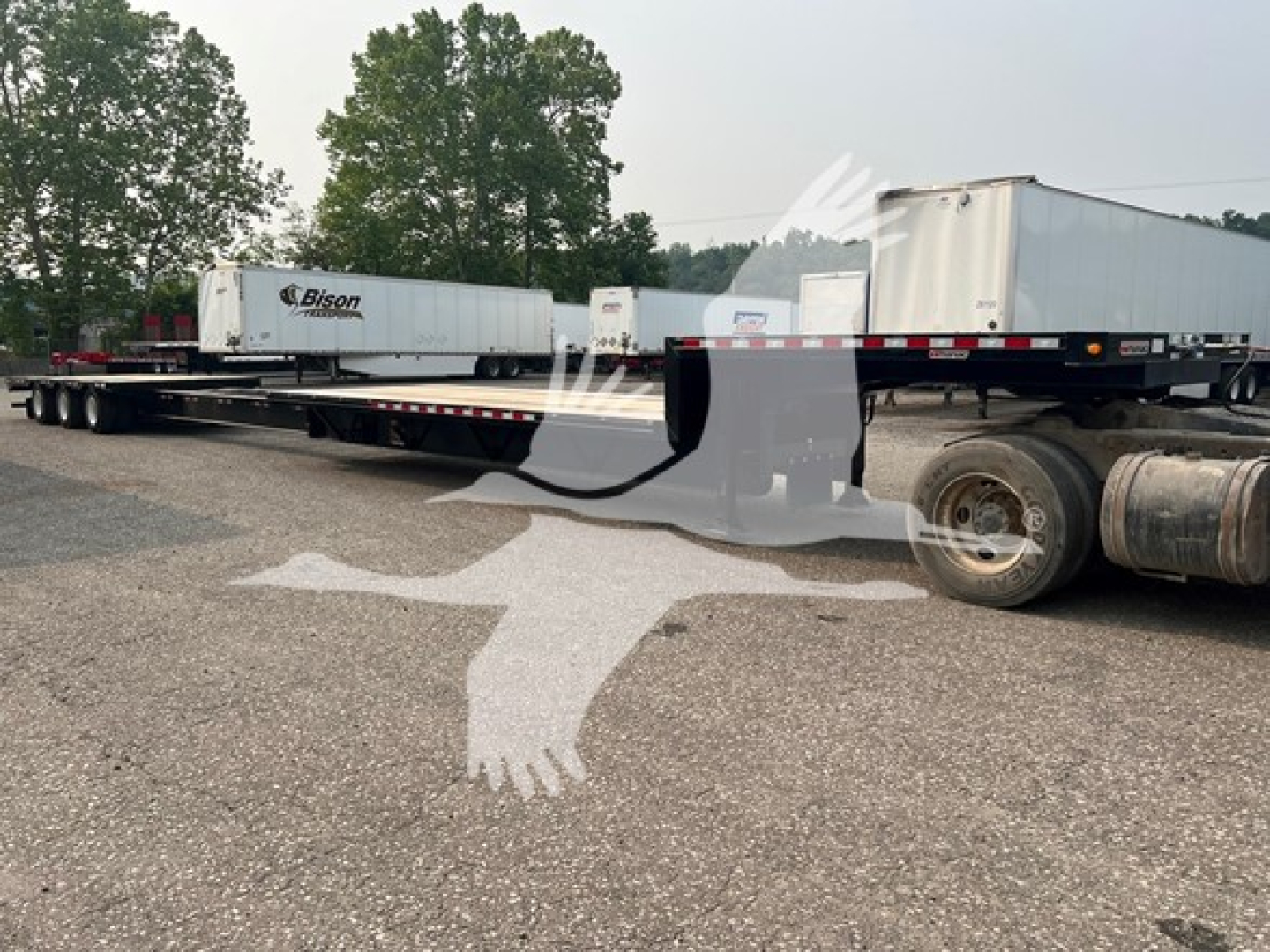 Manac steel drop extendable trailer in a yard, side view showing extendable deck sections and rear wheels.