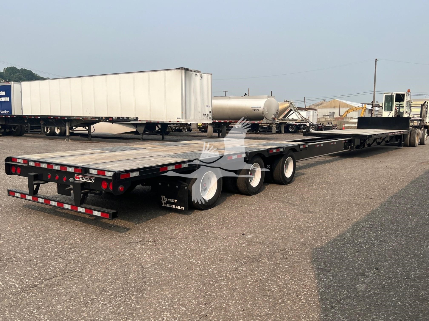 Manac steel drop extendable trailer in a parking lot with multiple axles and a low-bed design.