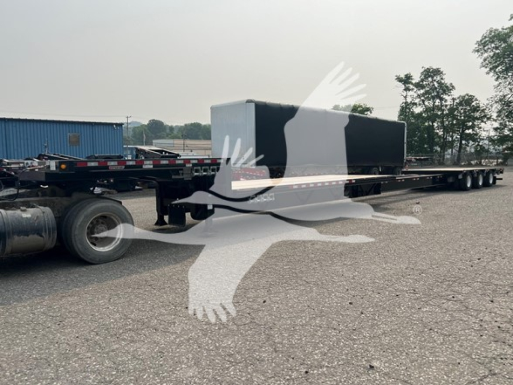 Manac steel drop extendable trailer with flatbed section and storage box, side view showing hitch and rear tandem wheels.