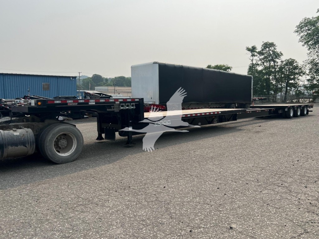 Manac steel drop extendable trailer in a storage lot showing a long flatbed with extendable section.