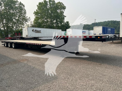 Trailer side view showing a low-profile drop deck extendable trailer with multiple axles and a white T-shaped cab logo watermark. Visible labels include Bison logo on a white trailer, and various shipping containers in background.