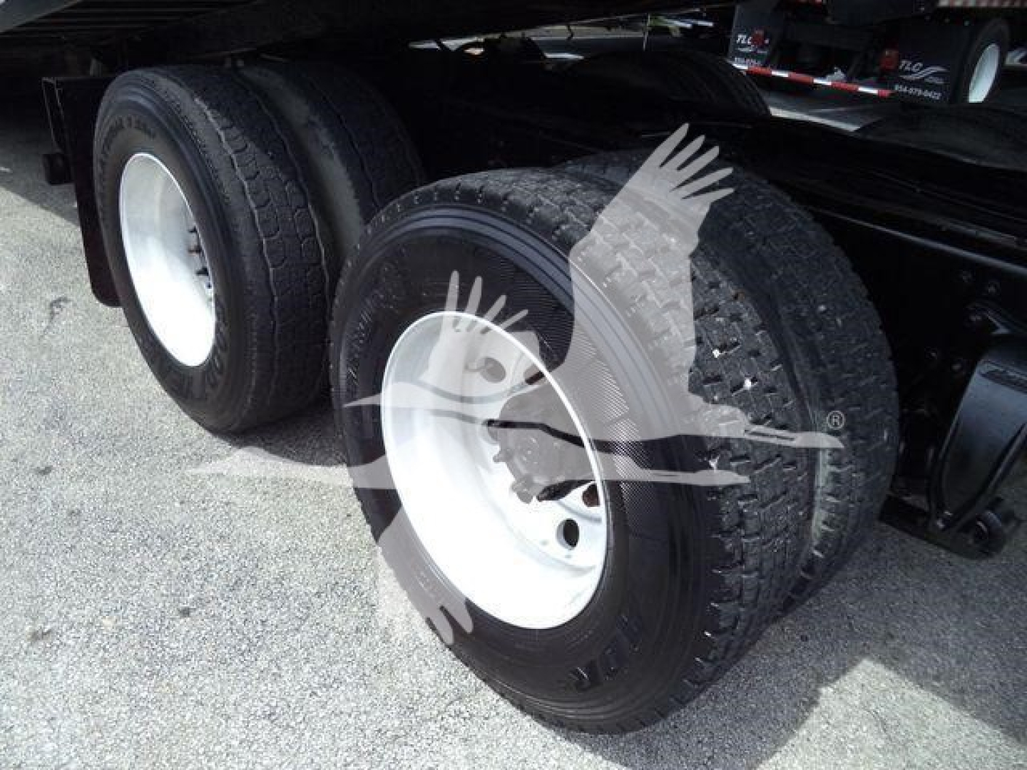 Dual rear axle wheels with black tires and white rims under a Freightliner M2 106 truck trailer chassis.