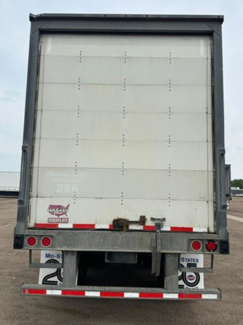 Rear view of a Wabash trailer with closed white back door. Visible text includes stock/IDs and bumper details: 'Wabash', '2' and '286' on lower left, 'STATES' near bumper, and various reflectors.