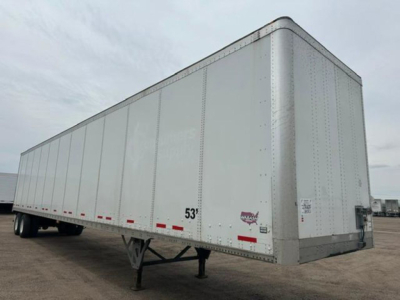 Semi trailer box showing a white 53' Wabash van with riveted aluminum panels and dual rear stairs on a dry lot.