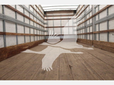 Truck trailer interior showing empty cargo space with wooden floor and metal side rails.