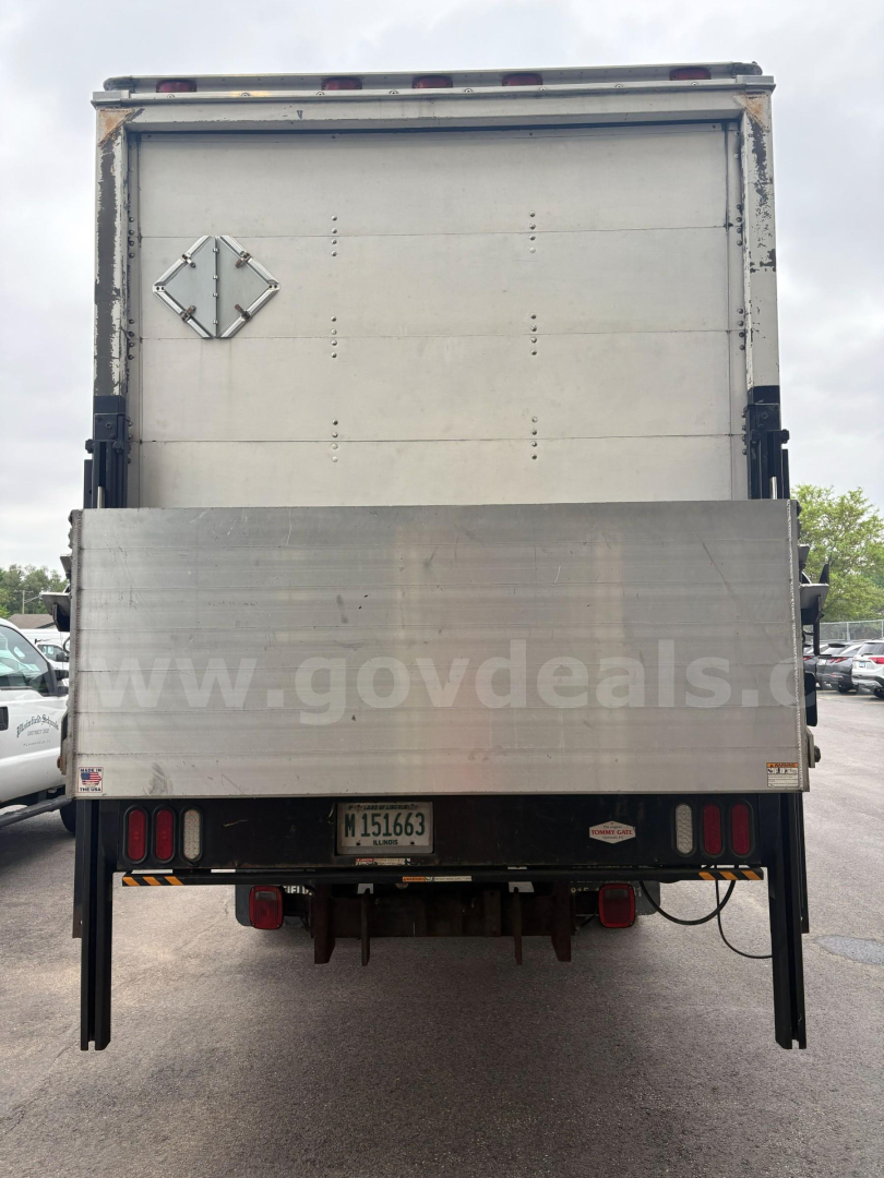 Rear view of a 2004 Ford F-650 box truck showing a large aluminum cargo door, reflective warning stripes, license plate M151663, and a faint website watermark www.govdeals.org on the lower panel.