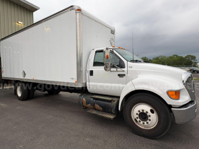 Box truck front cab and cargo box of a 2004 Ford F-650, white exterior, long rectangular box body, dual rear wheels, side steps, orange clearance light on cab roof.
