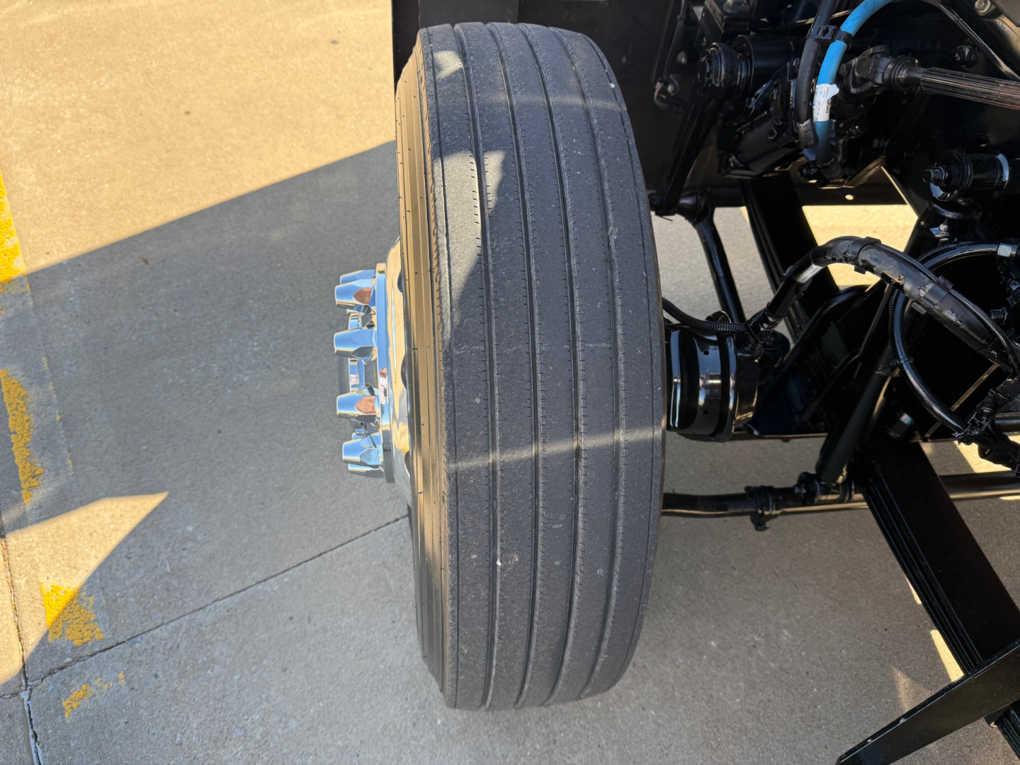 Kenworth W900L front axle showing a large single steer tire with alloy wheel and visible lug nuts.