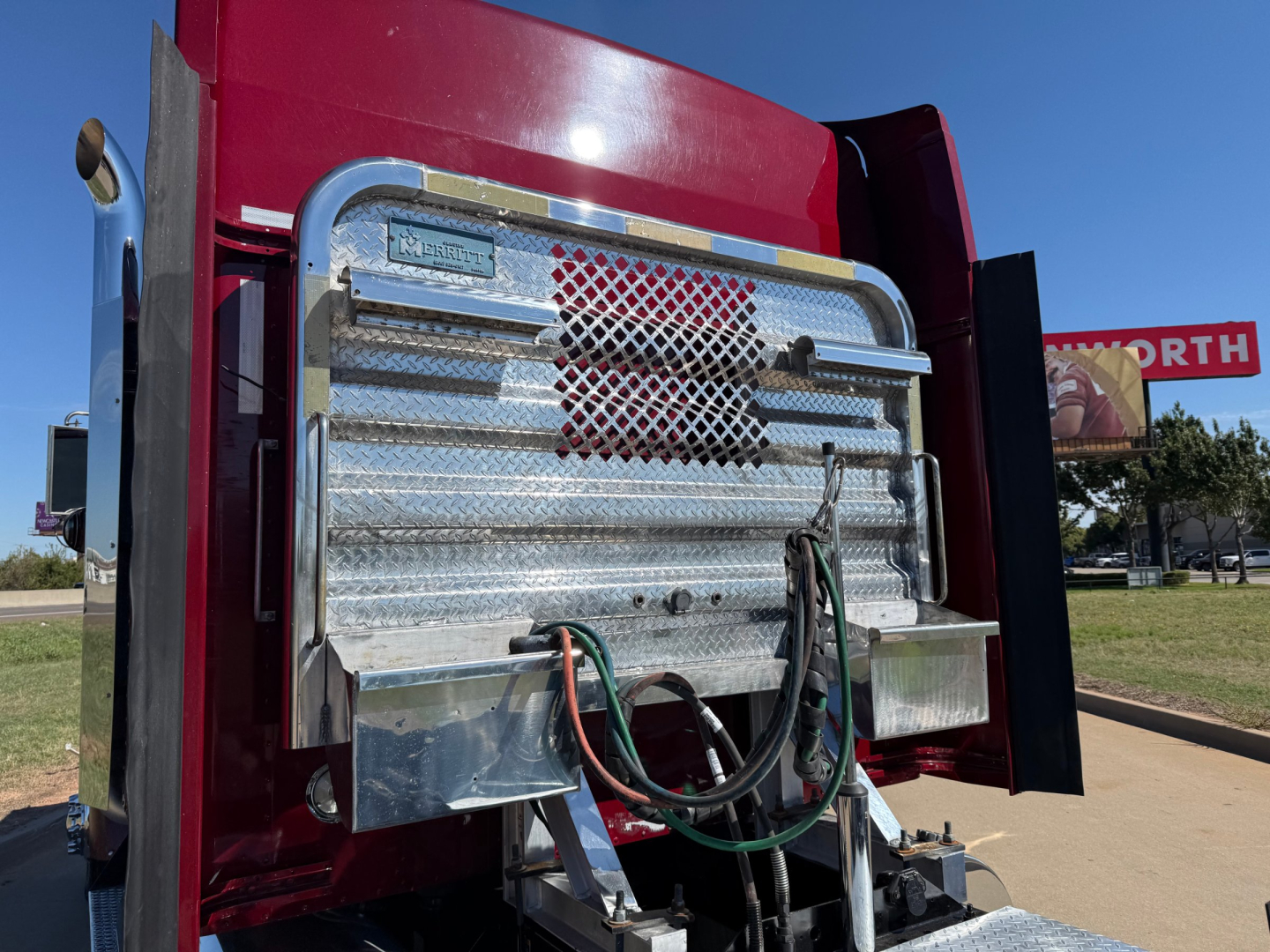 Kenworth W900L engine bay area showing chrome grille guard and multiple hoses connected to the front of the truck.