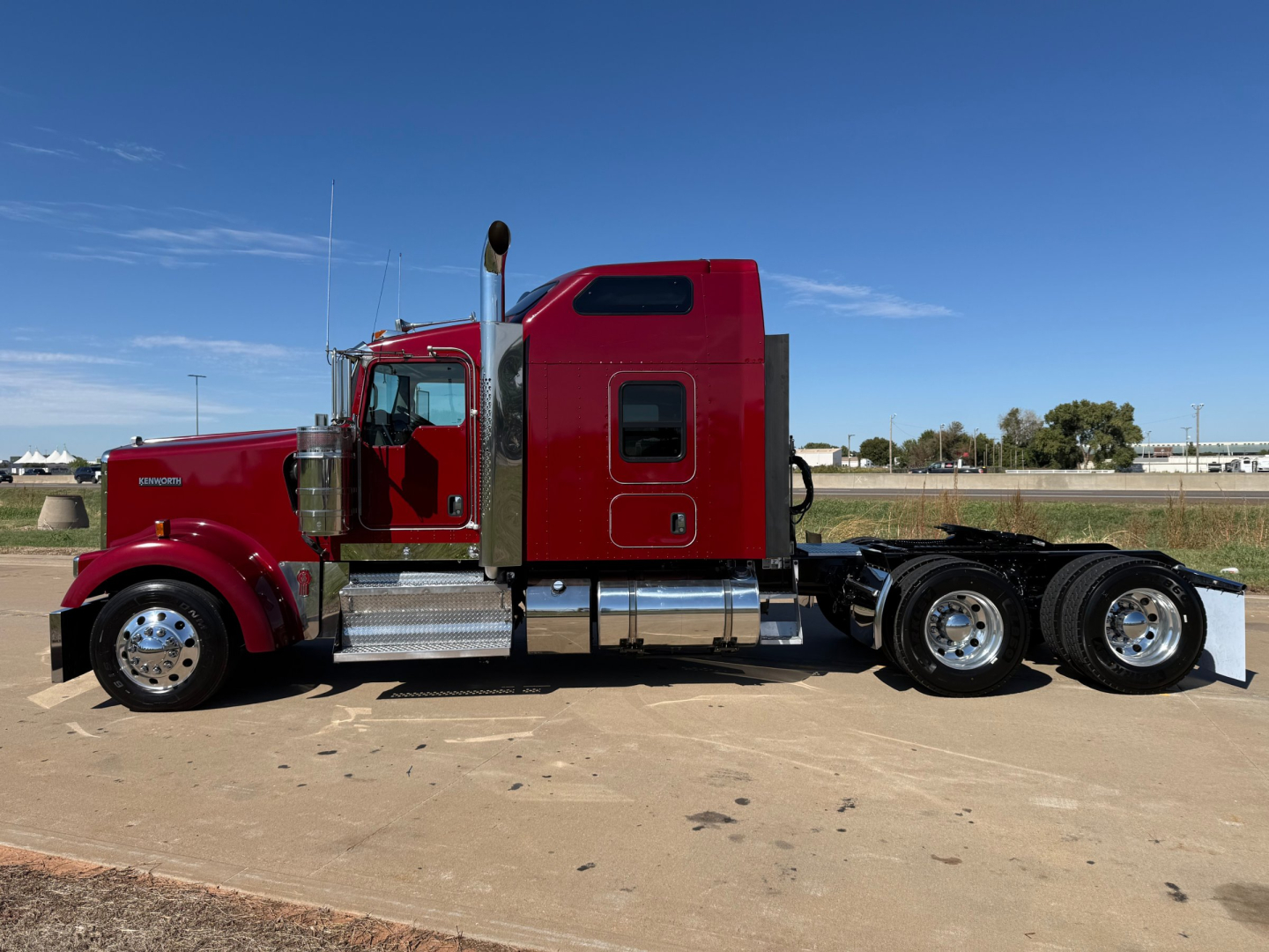 Kenworth W900L truck side view showing sleeper cab, chrome fuel tanks, and dual rear axles.