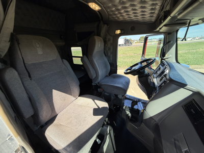 Kenworth W900L cab interior showing driver's seat, passenger seat, steering wheel, and dashboard with center console.