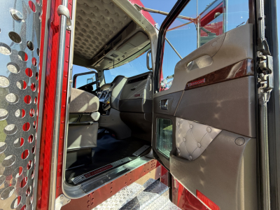 Kenworth W900L cab interior and open door showing driver's side with quilted brown door panel, step, and entry area.