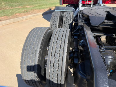 Dual rear drive tires on Kenworth truck chassis with visible suspension and fifth wheel, side view.