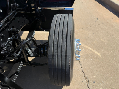 Kenworth W900L front dual rear dual-tire setup with suspension and wheel hub visible. No visible fluid labels or serials in this crop.