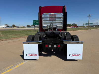 Kenworth W900L rear view showing chassis, dual rear axles, chrome fuel tanks, and mud flaps with MHC logos.