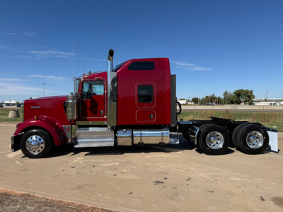 Kenworth W900L truck side view showing sleeper cab, chrome fuel tanks, and dual rear axles.