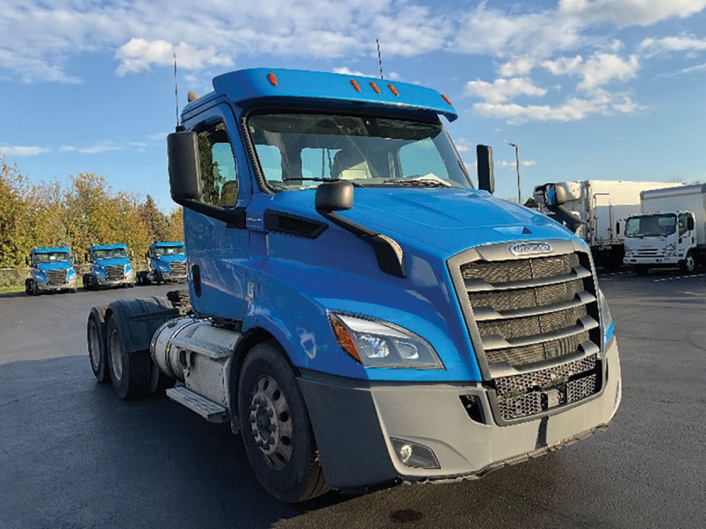 Freightliner Cascadia 116 daycab tractor in blue, front-right view, showing grille, headlights, bumper, and cab mirrors.