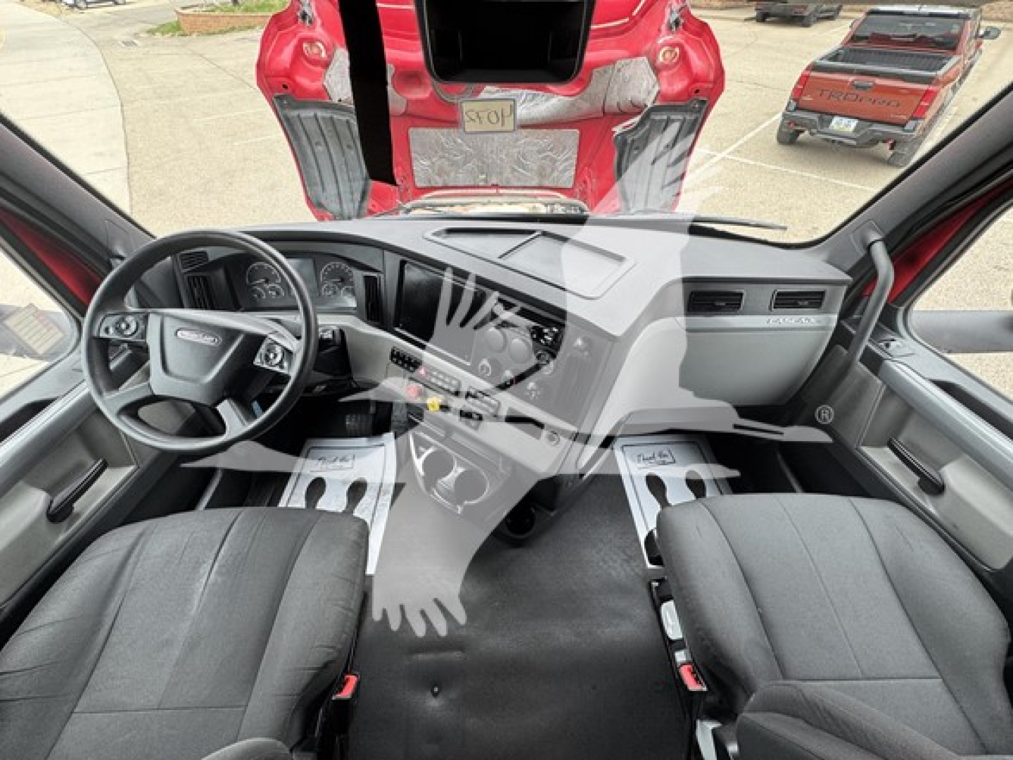 Dashboard and front cabin view of a 2022 Freightliner Cascadia 126 sleeper cab showing steering wheel, center console, and driver/passenger seats.