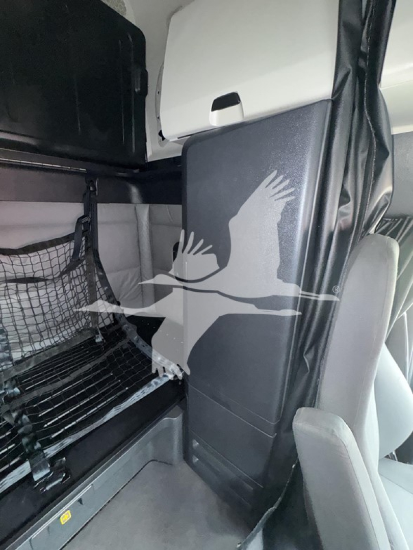 Truck cab interior showing bunk area and storage panels in a Freightliner Cascadia cab, with no readable textual labels visible.
