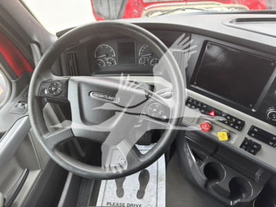 Freightliner Cascadia interior showing steering wheel, dashboard gauges, and infotainment touchscreen.