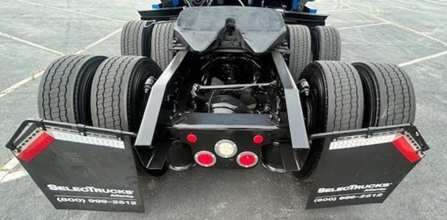 Rear view of a Freightliner Cascadia 126 tractor showing dual rear axles, mud flaps, and bumper with red circle lights.
