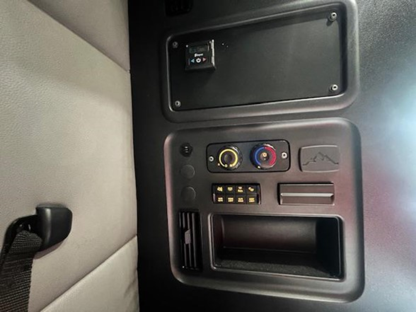 Freightliner Cascadia dash area showing climate control dials, airbags panel, and USB-like port; interior view with cup holder and switch panel.