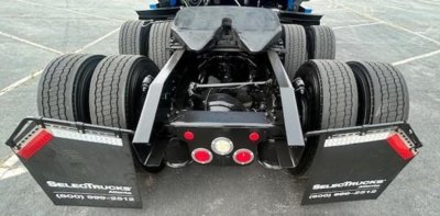 Rear view of a Freightliner Cascadia 126 tractor showing dual rear axles, mud flaps, and bumper with red circle lights.