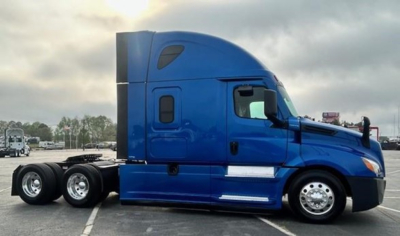 Truck side profile showing 2022 Freightliner Cascadia 126 cabin and blue exterior in a parking lot.