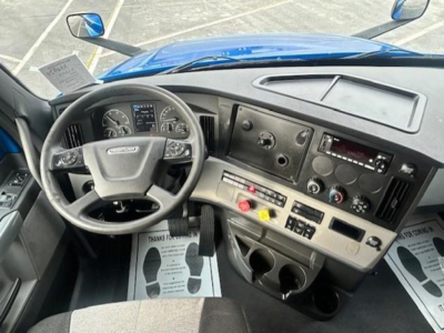 Interior of a Freightliner Cascadia truck cab showing steering wheel, dashboard, control panel, and center console.