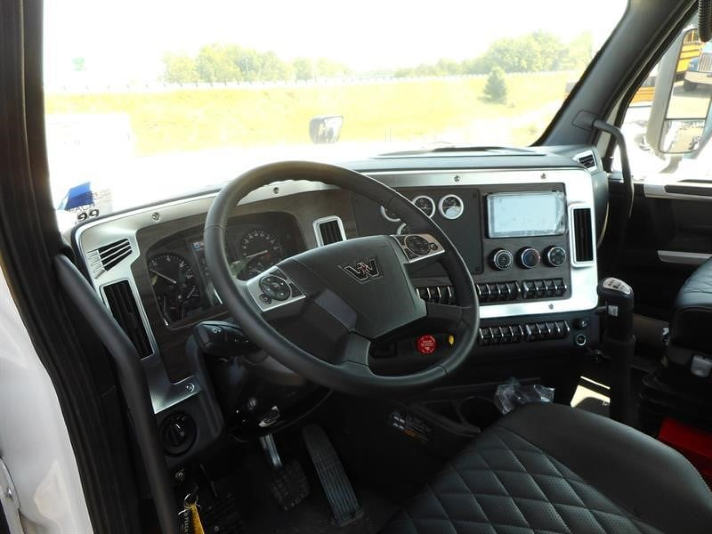 Truck cab interior showing steering wheel, dashboard with gauges, center touchscreen, and control panels in a modern Western Star truck.