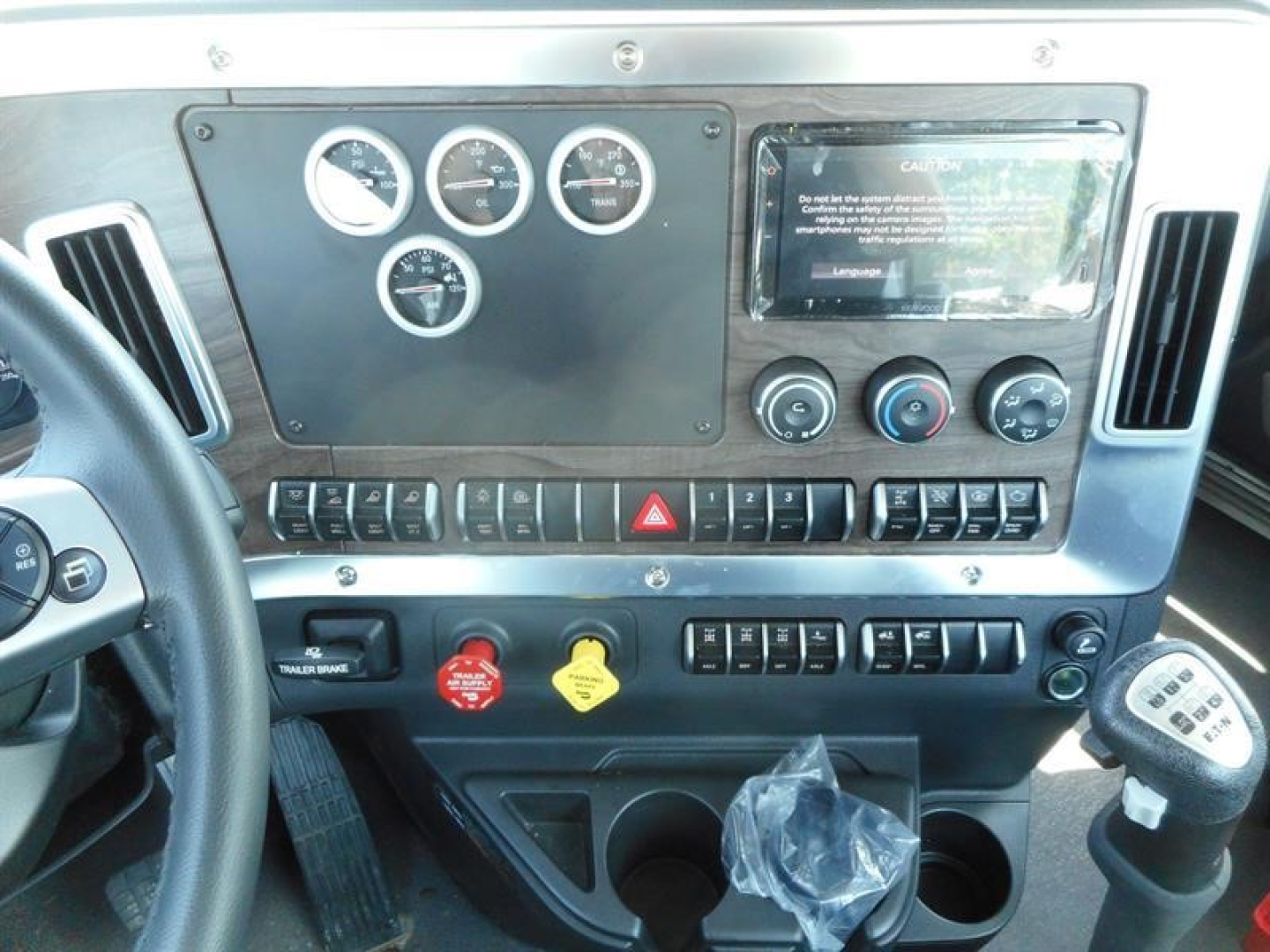 Dashboard panel of a 2027 Western Star 49X showing gauges, control switches, hazard button, and gear shifter; clean instrument cluster area.