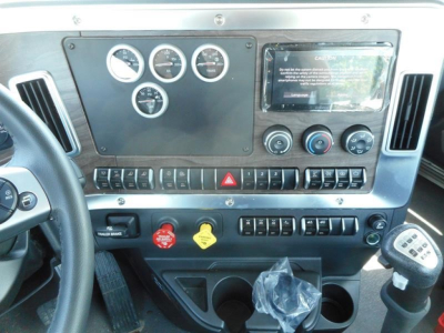 Dashboard panel of a 2027 Western Star 49X showing gauges, control switches, hazard button, and gear shifter; clean instrument cluster area.