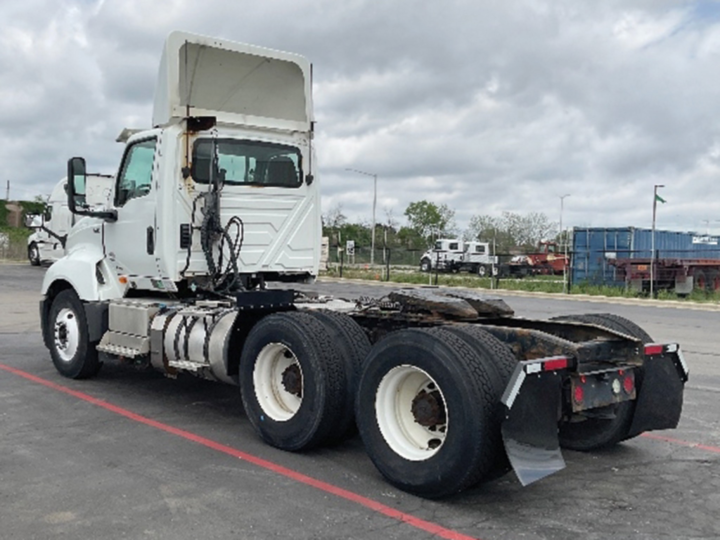 Vehicle side view showing a white International LT625 tractor with dual rear axles and fifth wheel missing; visible components include fuel tanks, exhaust, and hub wheels.