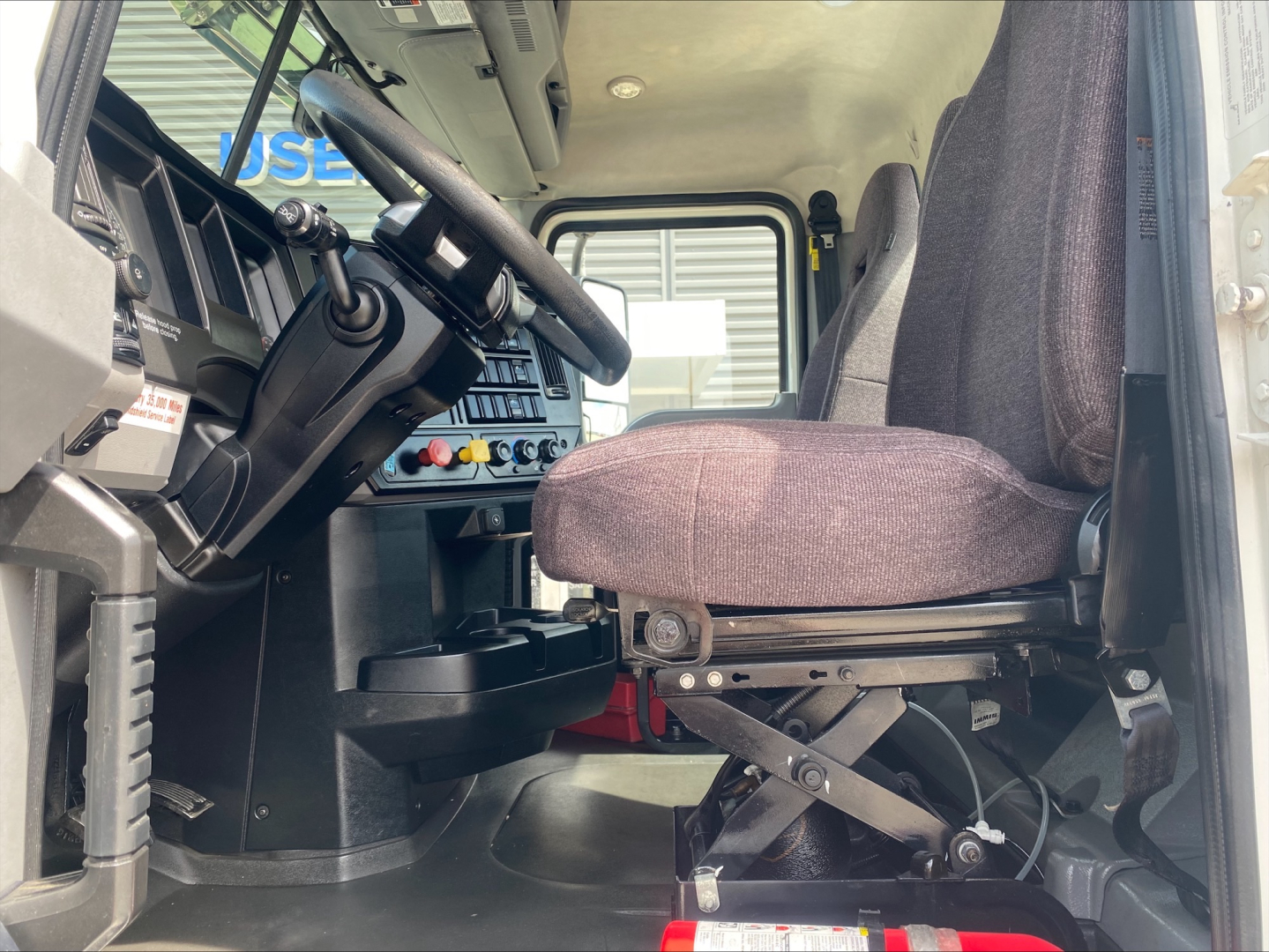 Cab interior of 2021 Mack AN42T showing steering wheel, dashboard controls, driver seat, and entry area.