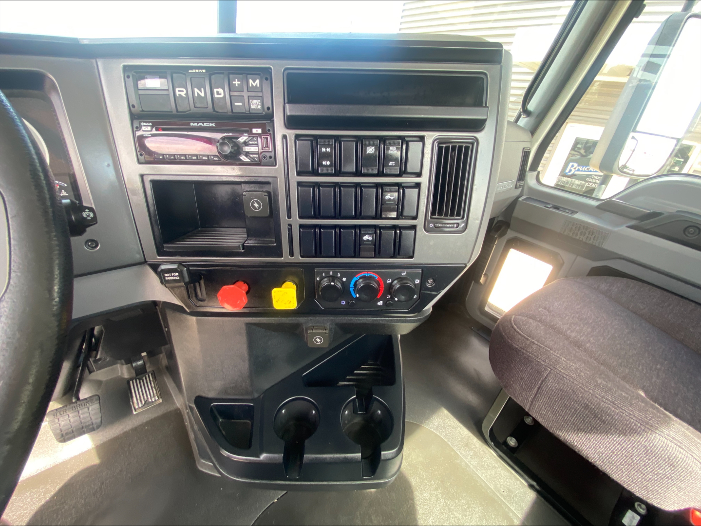 Truck dashboard with gear selector showing R N D B and various switches; center console has gauges, climate controls, and storage compartments.