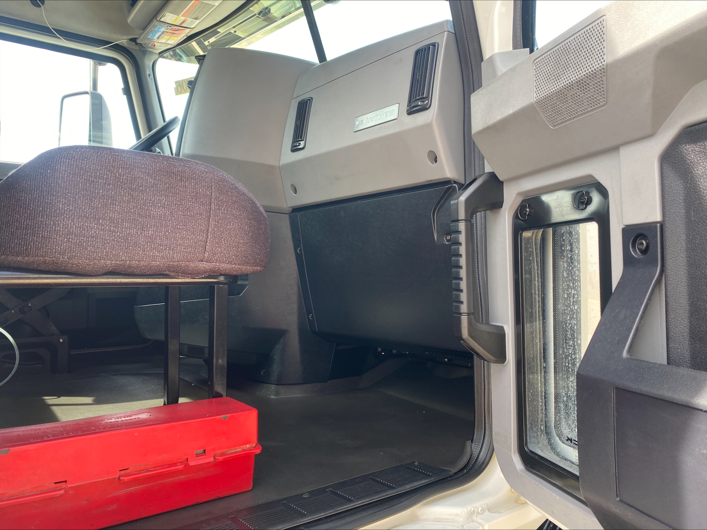 Truck cab interior showing passenger seat, dashboard panels, and door area from the driver side in a Mack AN42T conventional daycab.