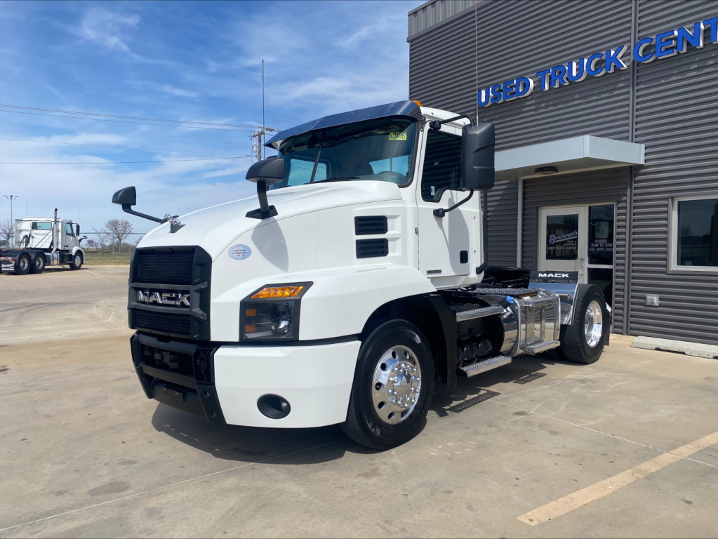 White 2021 Mack AN42T conventional daycab truck parked outside a used truck center showing front and side view.
