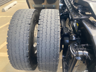 Dual rear wheels and suspension of a 2021 Mack AN42T tractor showing dual tires and part of the drivetrain.