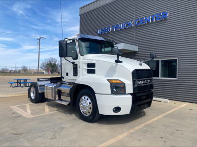 Mack AN42T conventional daycab truck parked outside a Used Truck Center; white exterior, large black grille, side fuel tanks, dual rear wheels.